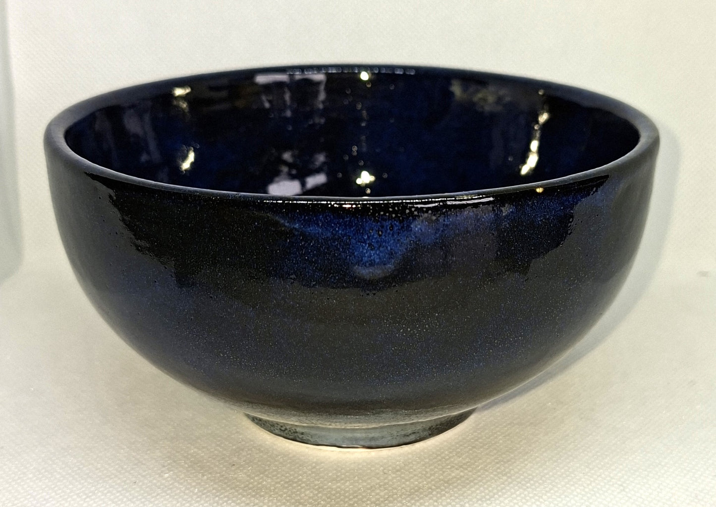 Glossy black ceramic bowl on a light gray background