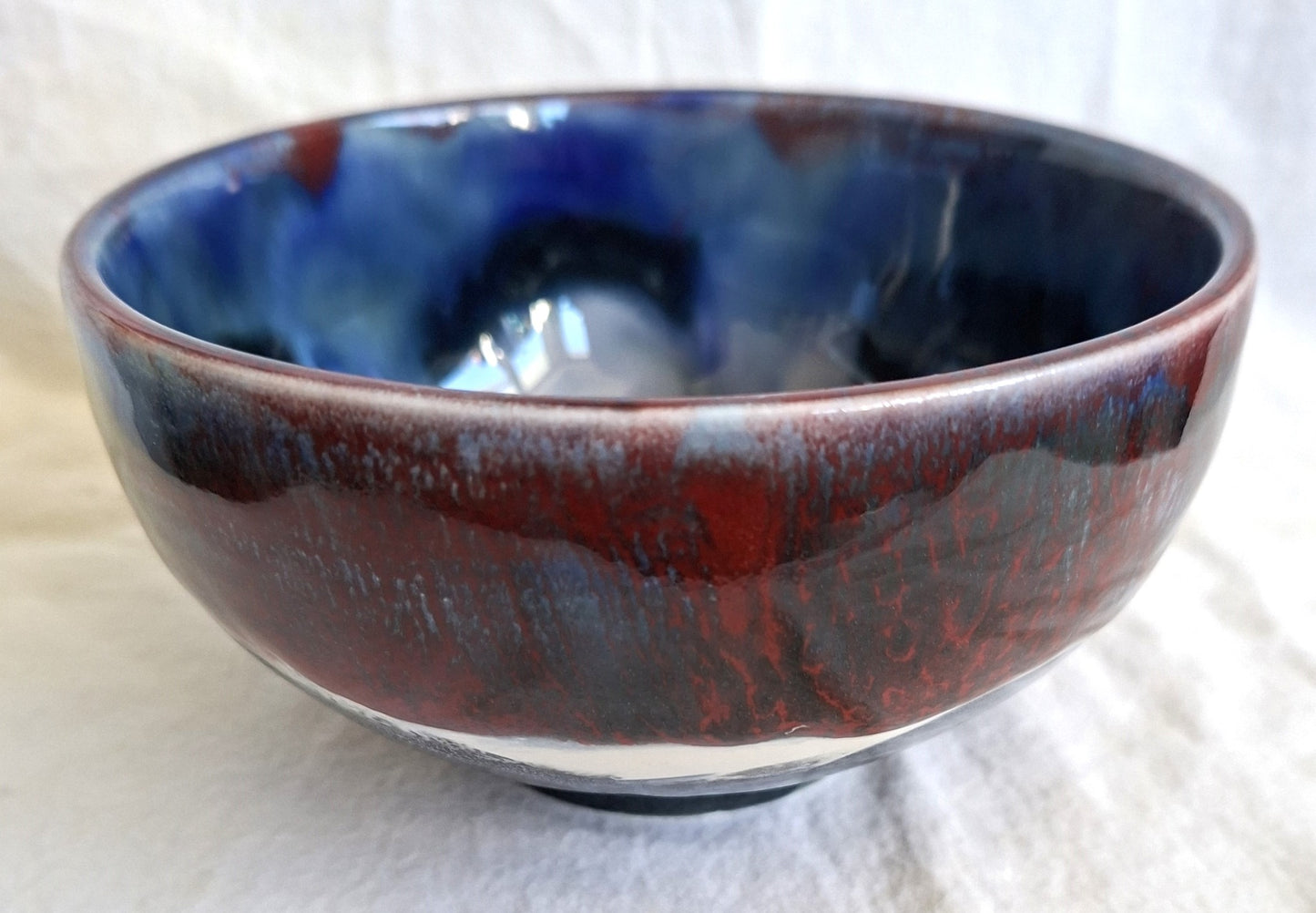 Ceramic bowl with blue and red glaze on a white background