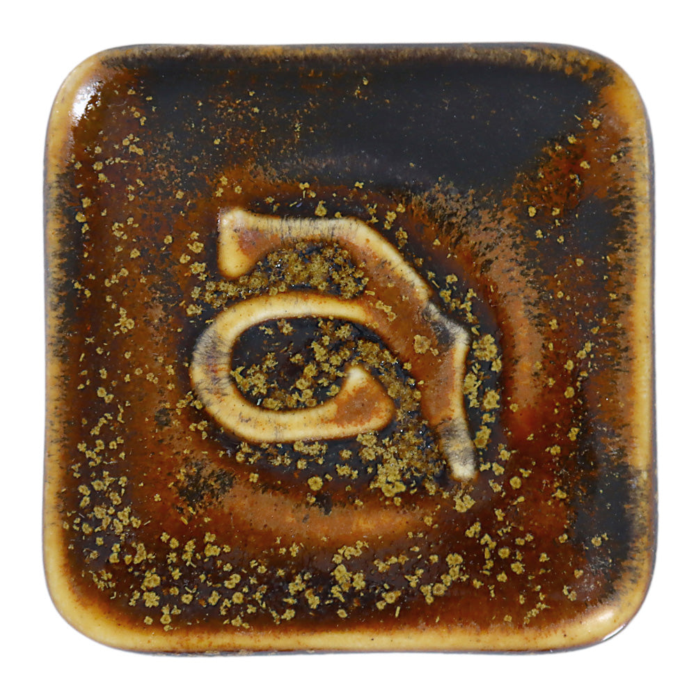 Abbots Gold Dust glaze swatch showing darker areas pool while lighter highlights break across edges, producing a surface full of depth and contrast.