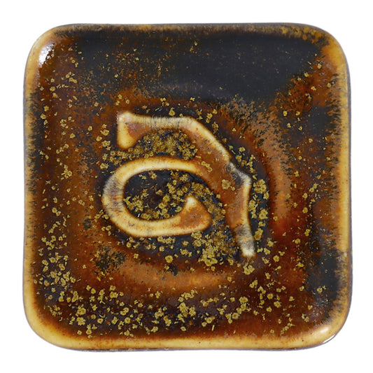 Abbots Gold Dust glaze swatch showing darker areas pool while lighter highlights break across edges, producing a surface full of depth and contrast.