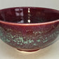 Ceramic bowl with maroon and green glaze on a white background